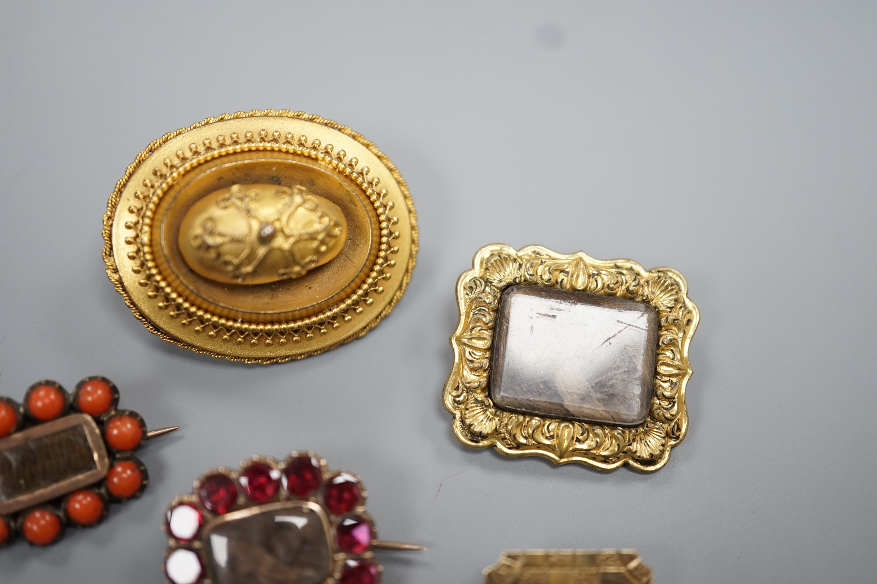 Two 19th century gilt metal and plaited hair set mourning brooches, two other mourning brooches and an oval pinchbeck brooch, largest 34mm.